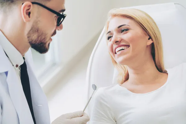 Woman smiling while oral surgeon talks.